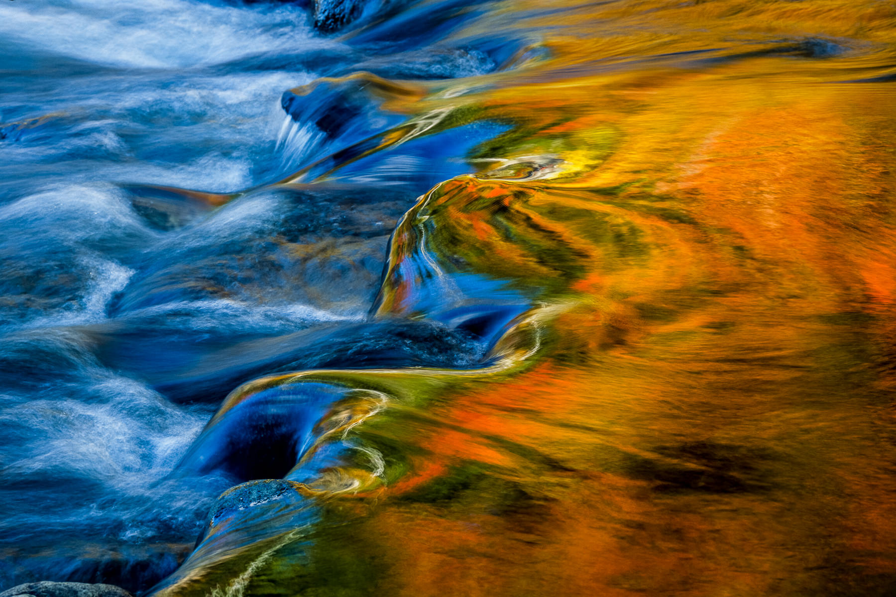 Photograph of uutumn colors reflecting over running water, New Hampshire, taken by Gil Lopez-Espina